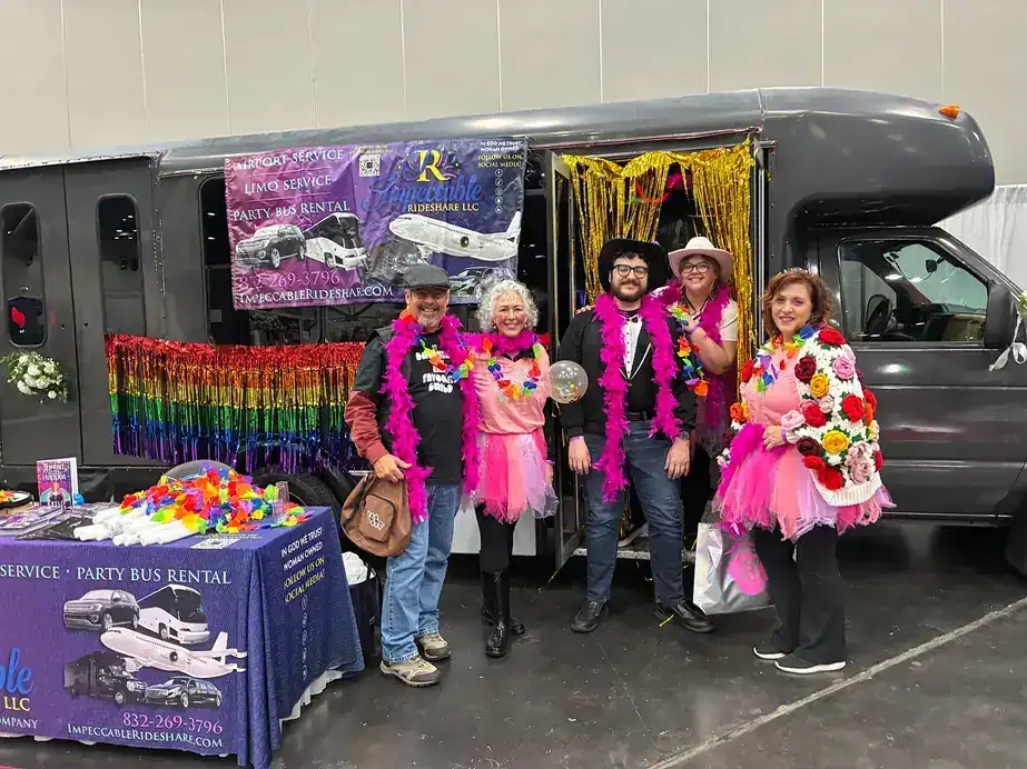 The Impeccable Rideshare team standing at an expo stand in front of the bus